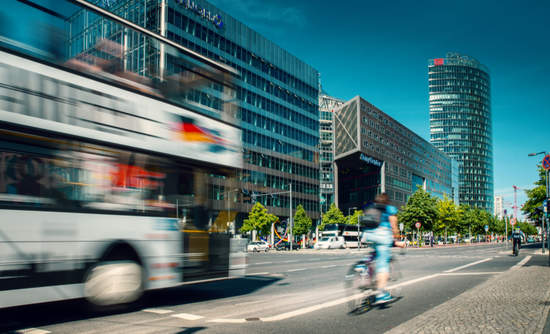 Cyclist riding alongside a bus at Potsdamer Platz in Berlin, Germany. 骑车人骑在旁边波茨坦广场在柏林,德国的总线。